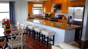 Una cocina moderna con armarios de madera, un refrigerador de acero inoxidable y una barra con taburetes.