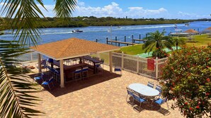 Un patio con mesas y sillas, una piscina y vistas al agua con barcos.