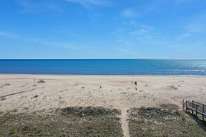 A beach with a wooden walkway and a bench. - Amethyst Dunes (Port St. Joe)