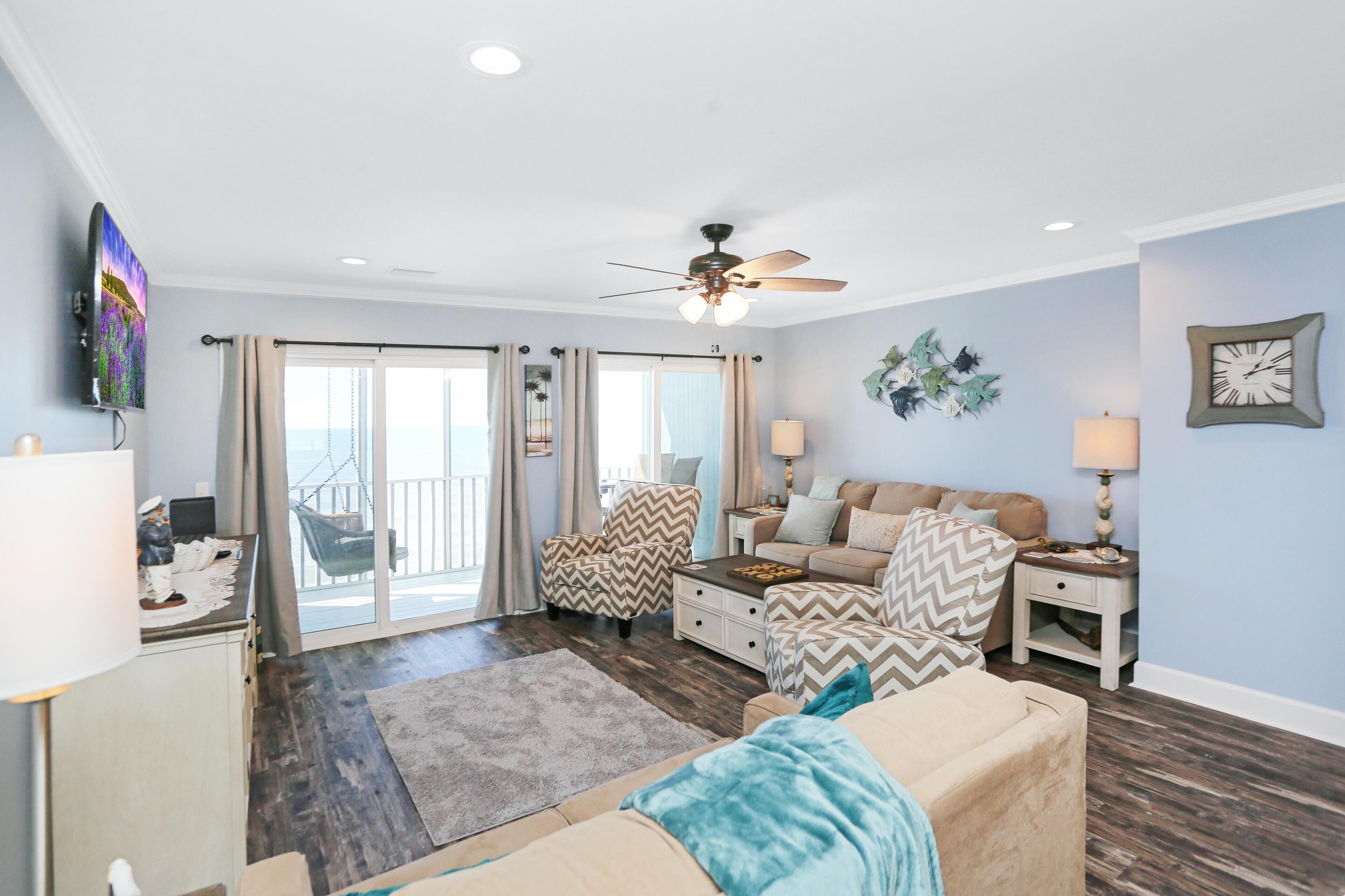 A living room with a ceiling fan, a sofa set, a coffee table, and a TV.
