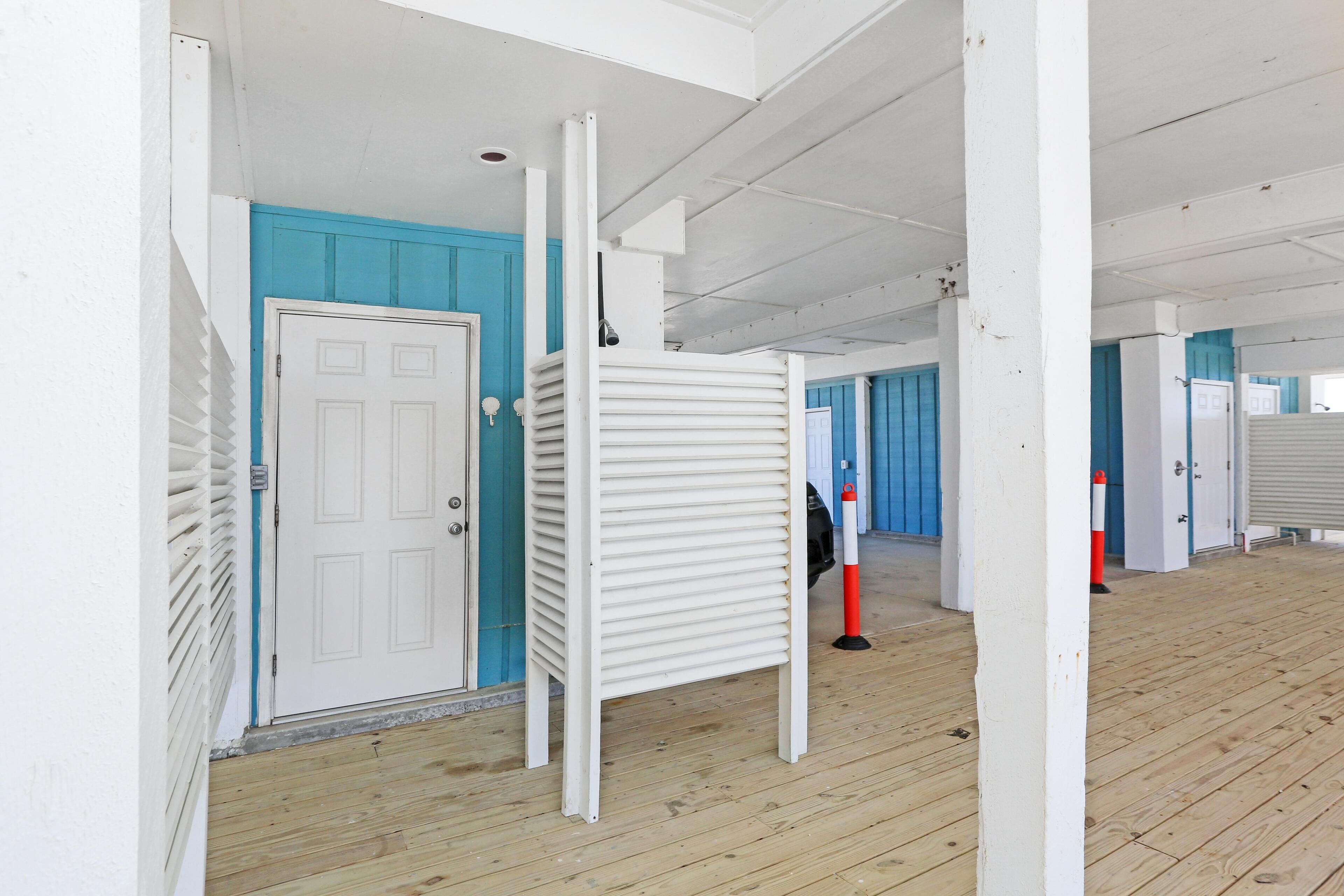 A corridor with white walls, blue doors, and a wooden floor.