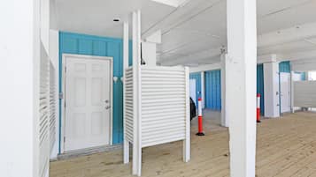 Un couloir aux murs blancs, aux portes bleues et au plancher en bois.
