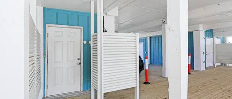 A corridor with white walls, blue doors, and a wooden floor.