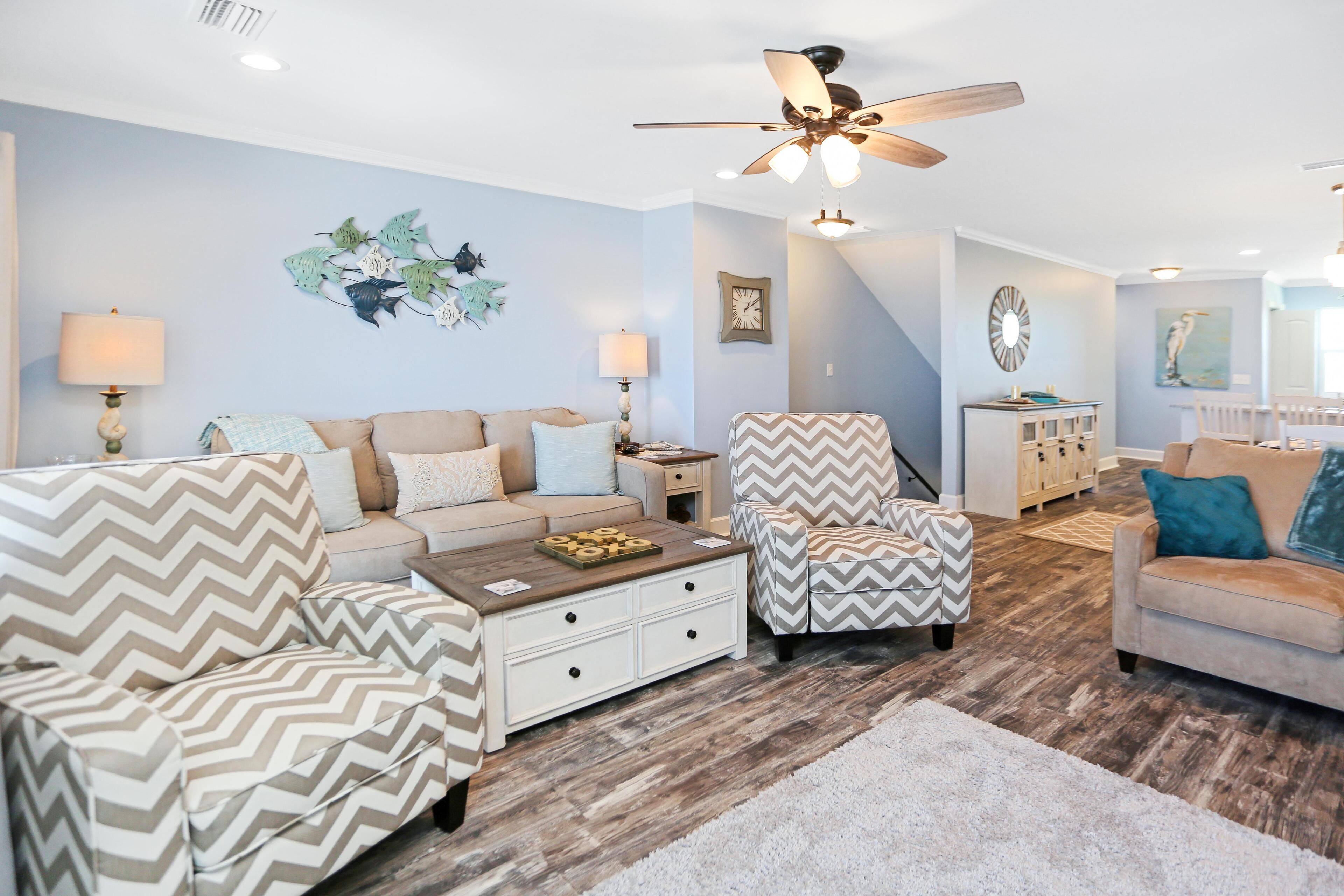A living room with a sofa, armchairs, a coffee table, and a ceiling fan.