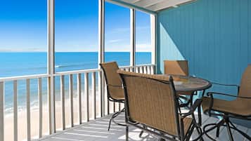 A covered outdoor area with a view of the ocean, featuring a table and chairs.