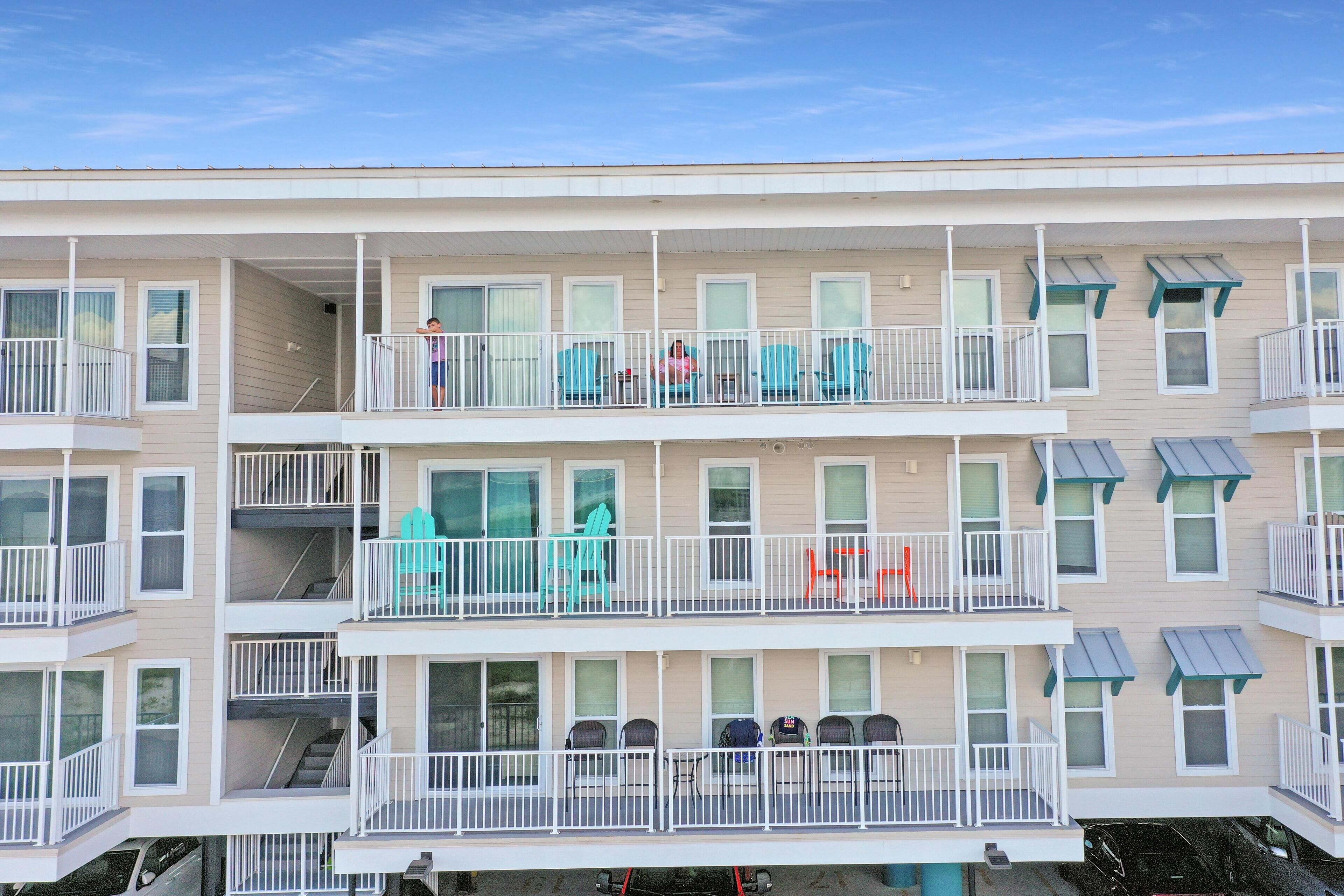 A multi-story residential building with balconies, windows, and a parking area.