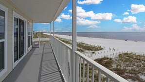 Un balcon donnant sur la plage, avec vue sur l’océan et le rivage.
