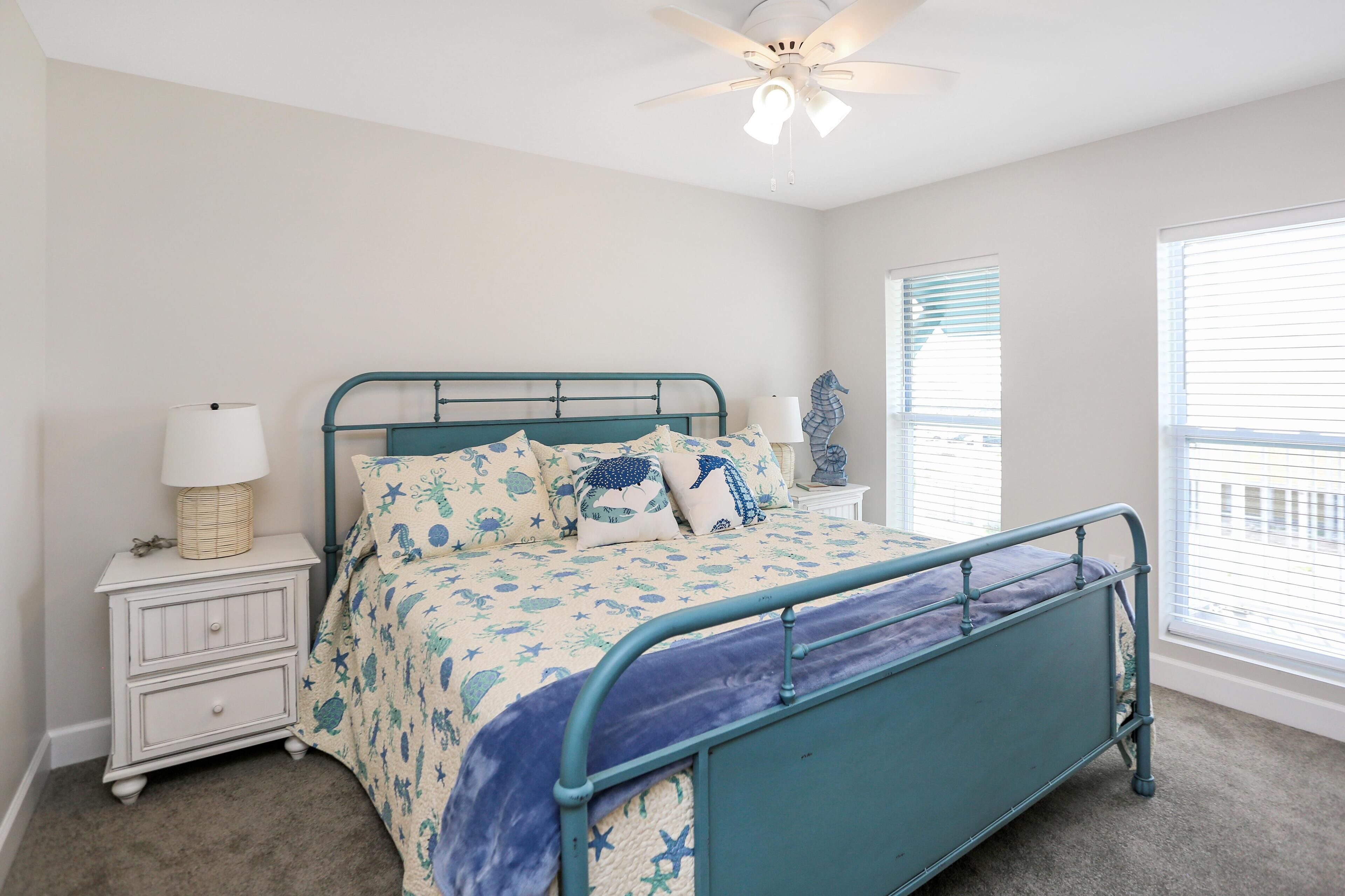 A bedroom with a bed, nightstand, lamp, and ceiling fan.