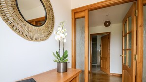 A wooden desk with a notebook, a woven mirror, and a potted orchid. - Kilnary Cottage (Ellon)