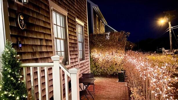 A wooden house with a porch, a Christmas tree, and string lights. - Nantucket Guest House (Nantucket)