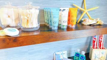 Une étagère de salle de bain contenant des articles de toilette, notamment des cotons-tiges, du shampoing, de l’après-shampoing et du dentifrice.