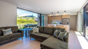 A modern living room with a sectional sofa and a dining area with a table and chairs. - 2 min walk to the glorious white sands of Onetangi beach (Waiheke Island)