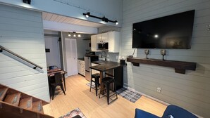 A compact living space with a kitchen, dining area, and a TV mounted on the wall.