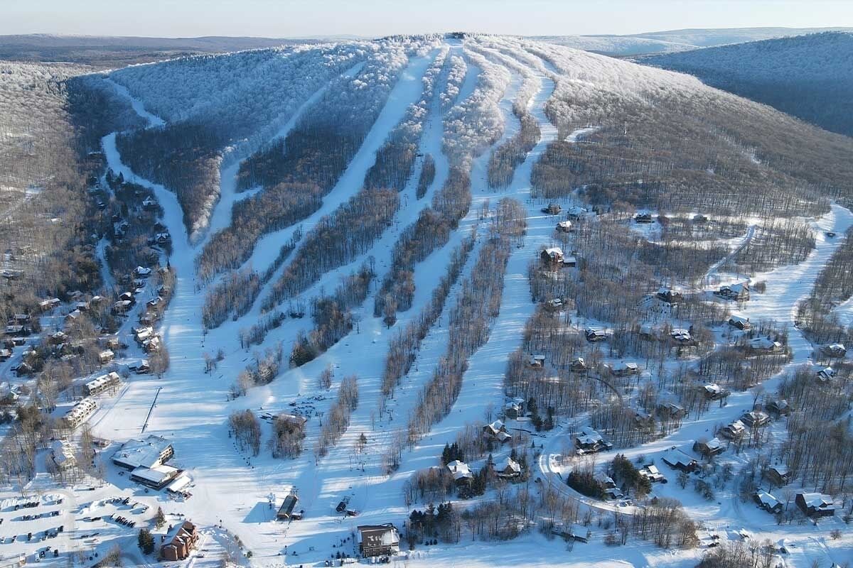 Un paysage enneigé avec une station de ski, comprenant des pistes de ski et des chalets.