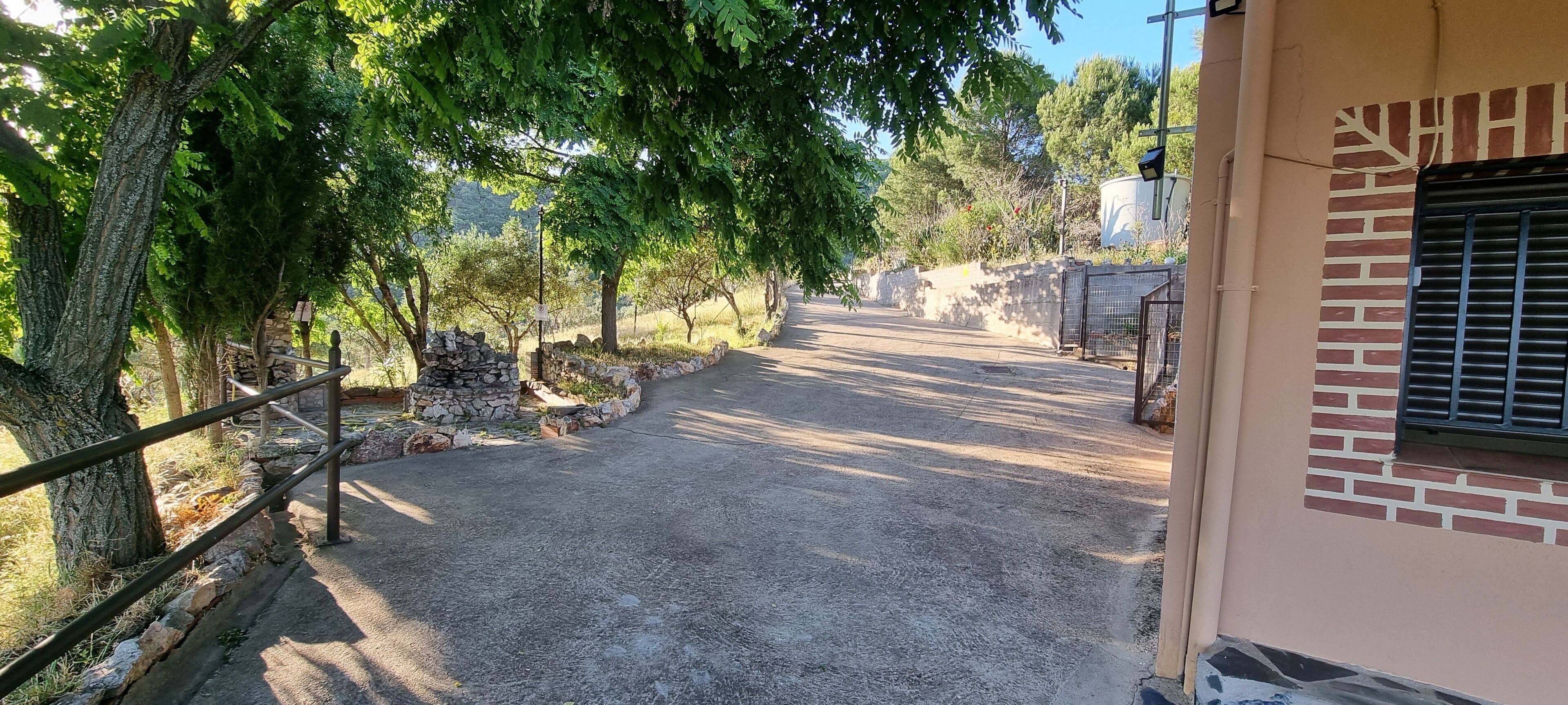 Un chemin pavé mène à un bâtiment doté d’un mur en pierre et d’une porte en métal.