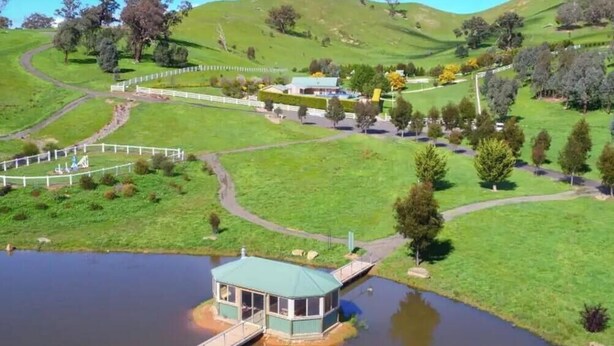 A lakeside property with a gazebo, pathways, and a fenced area.
