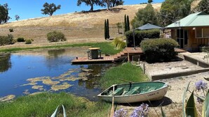 A serene lakeside setting with a dock, a small boat, and a building with a green roof.