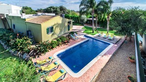 A swimming pool with lounge chairs, surrounded by a garden and a small building. - Rustic Villa with pool near Olhao (Moncarapacho)