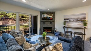 A modern living room with a fireplace, a large TV mounted on the wall, and a comfortable seating area. - Total Renovation 300' from Chili Express (Angel Fire)