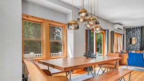 A dining area with a wooden table and benches, large windows, and a blue sofa.