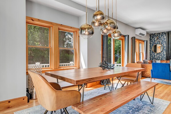 Un espace repas avec une table et des bancs en bois, de grandes fenêtres et un canapé bleu.