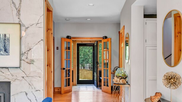 A hallway with wooden doors, a marble wall, and a blue sofa.