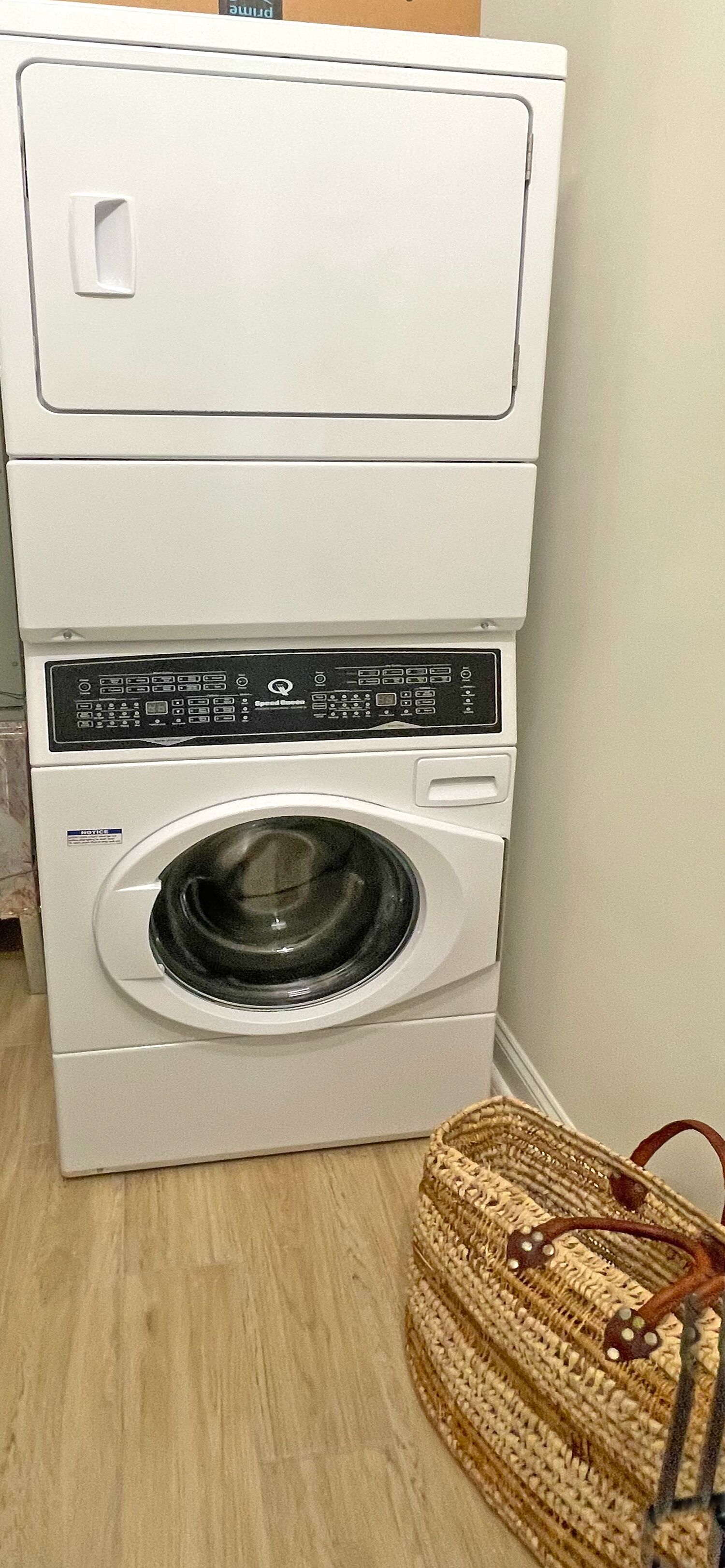Una lavadora de carga frontal con panel de control, un cesto y piso de madera.