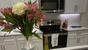 Un comptoir de cuisine orné d’un vase de fleurs, d’une bouteille de vin, d’une portion de fromage et d’une bougie.