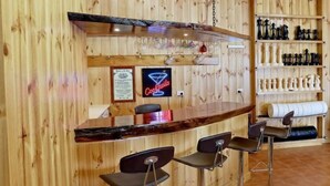 A bar area with wooden paneling, a neon cocktail sign, and a chessboard display.