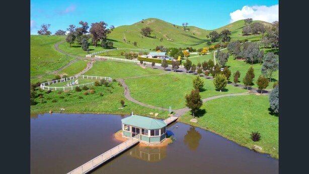 A lakeside property with a dock, a gazebo, and a fenced area with a building.