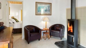 Una sala de estar acogedora con chimenea, dos sillones de cuero, una mesita con lámpara y un cuadro en la pared.