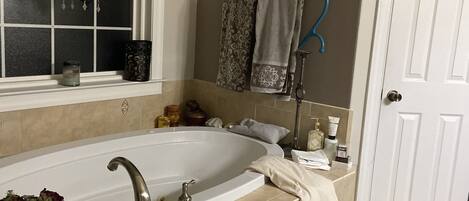 Ein Badezimmer mit einer großen Badewanne, einem Fenster mit einem Chandelier und einer Tür.