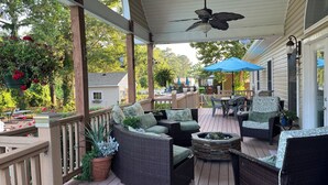 A covered outdoor deck with wicker furniture, a ceiling fan, and potted plants. - Island home on the water with pool.  Bring your boat or jet skis ! Golf near by (Currituck)