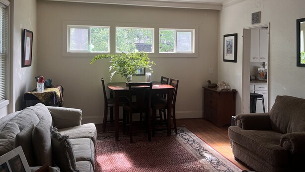A dining area with a table, chairs, a potted plant, and a window with a view of trees. - ♥️ of UofO pristine residence for the World Championships (Eugene)