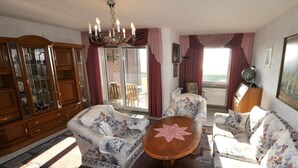 Ein Wohnzimmer mit Sofas mit floralem Muster, einem Holzschrank, einem runden Tisch und einer Kristallleuchter.
