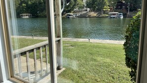 Une vue depuis une fenêtre donnant sur un lac, avec des bateaux, un quai et un bâtiment en arrière-plan.