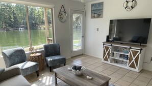 Un salon doté d’une grande fenêtre donnant sur un lac, d’un téléviseur et d’une table basse en bois.