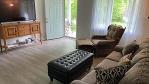 Un salon comprenant un téléviseur, un canapé, un fauteuil et un meuble en bois.