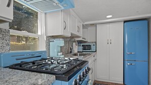 A kitchen with a blue stove, white cabinets, a microwave, and a blue refrigerator. - Downtown Big Sky Bungalow w/AC, Fully Fenced Yard, W/D, 2 Smart TVs, Speedy WiFi (Flagstaff)