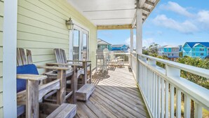 A wooden deck with chairs and a table, overlooking a row of colorful houses. - Sea Breeze Manor (Port St. Joe)