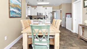 A dining area with a wooden table and chairs, a chandelier, and a kitchen in the background. - Sea Breeze Manor (Port St. Joe)