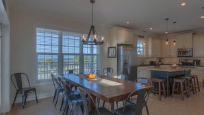 A spacious kitchen with a large island, modern appliances, and ample natural light from large windows. - Veranda Views (Port St. Joe)
