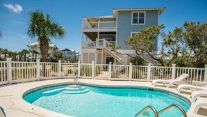A swimming pool with a slide, surrounded by a white fence, and a two-story building with balconies in the background. - Veranda Views (Port St. Joe)
