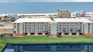 Et stort hotel med flere etager, en swimmingpool og udsigt til stranden og havet.
