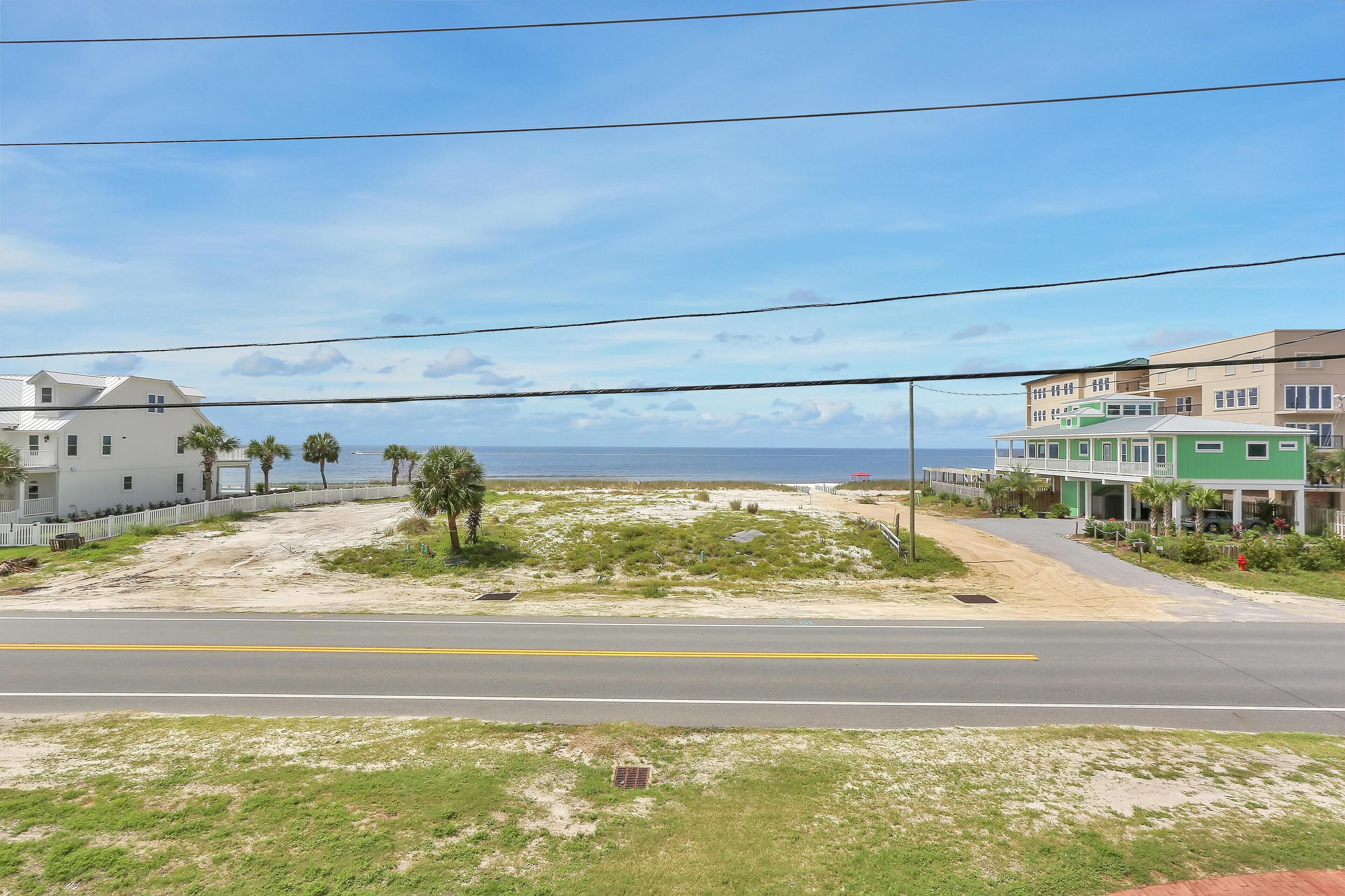 Eine Küstenstraße mit Blick auf den Strand, ein weißes Gebäude und ein Gebäude mit Veranda, das grün gestrichen ist.
