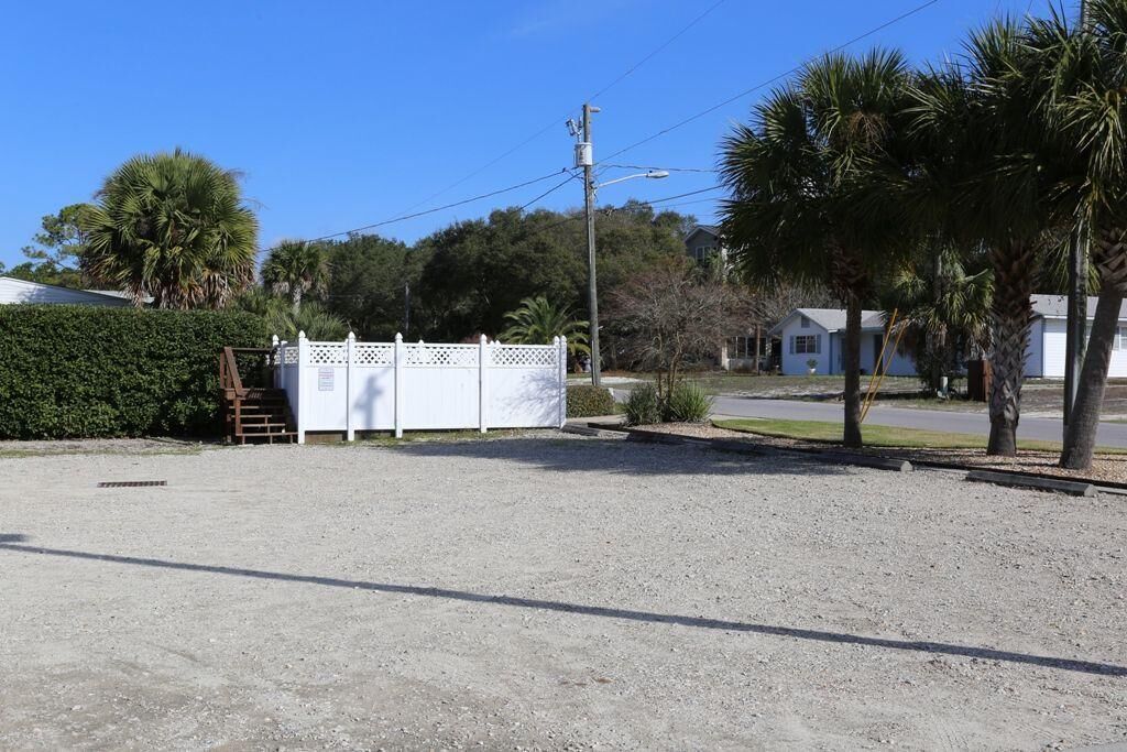 A gravel parking area with a white fence and a utility pole.