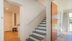 Eine Treppe mit weißen Wänden und grauen Stufen, die zu einem Raum mit Holzboden führt.