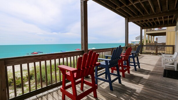 A wooden deck with red and blue Adirondack chairs overlooking a beach. - A Turtle View (Port St. Joe)