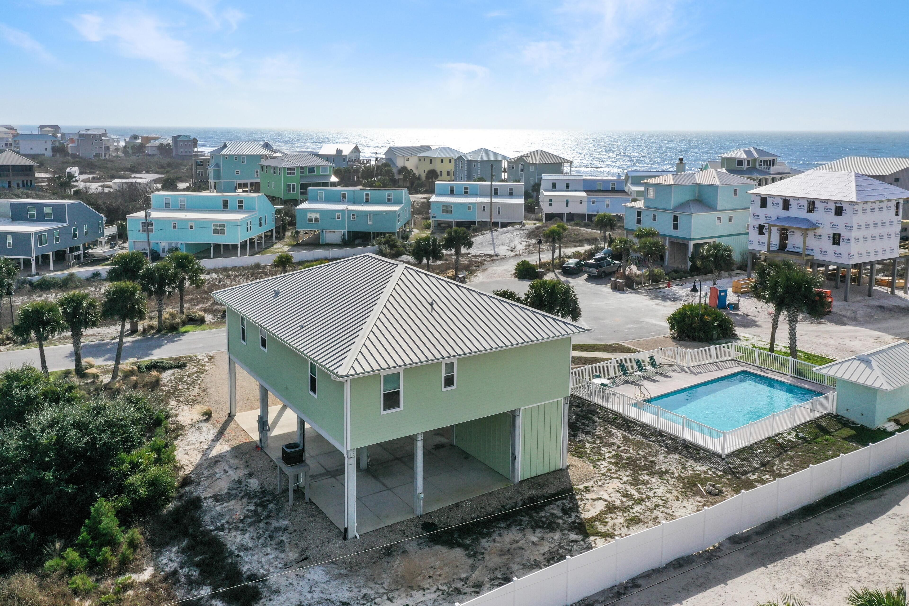 A coastal residential area with light-colored houses, a swimming pool, and a view of the ocean.