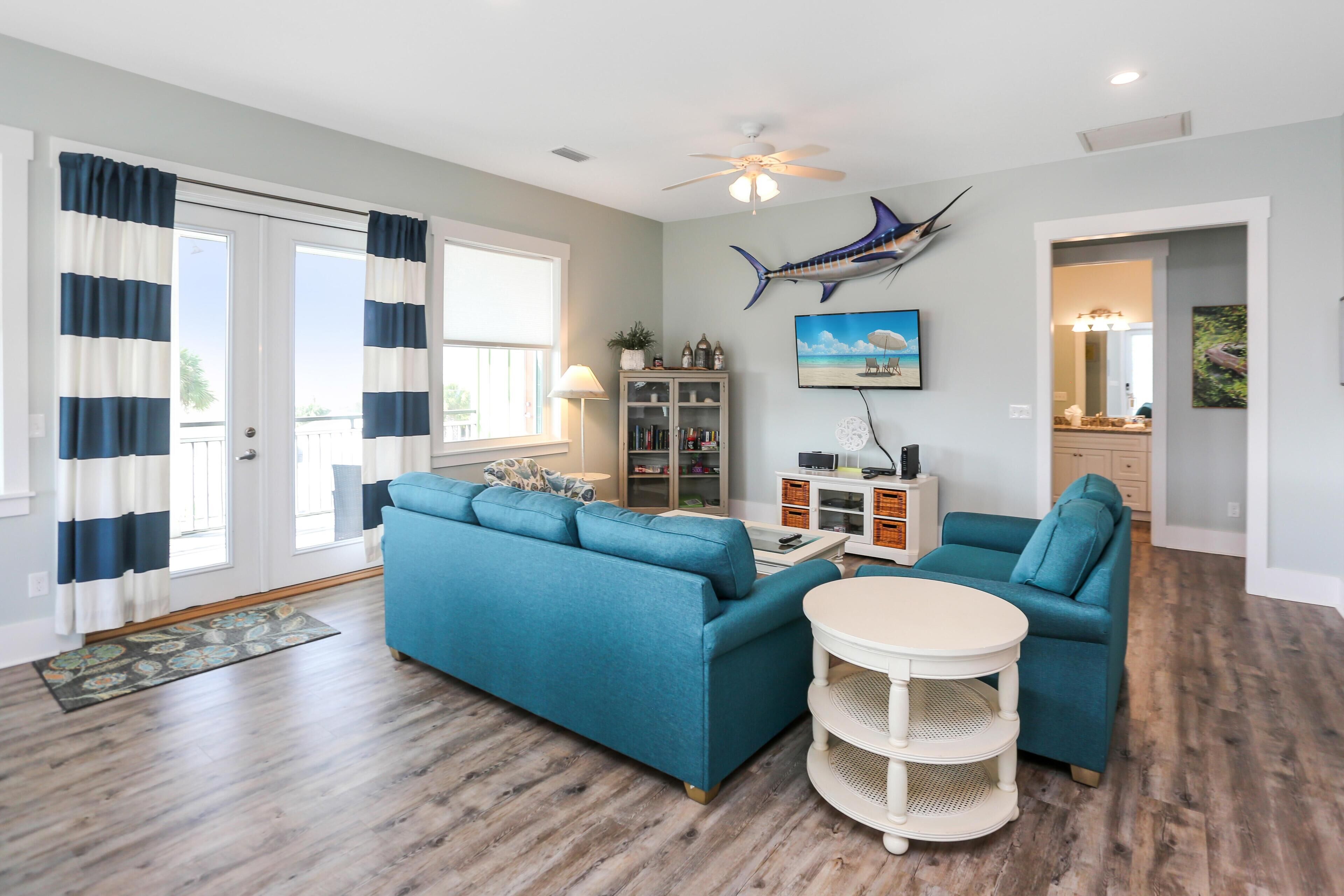 A living room with a blue sectional sofa, a white coffee table, and a ceiling fan.